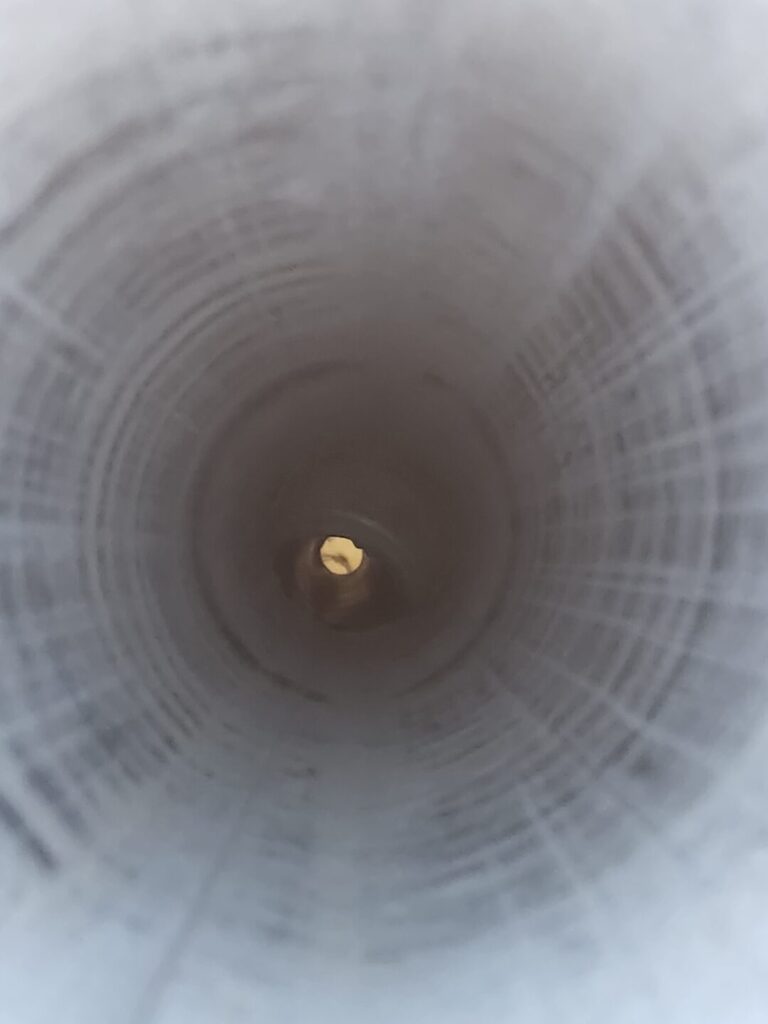 View down the inside of a metal dryer vent duct after cleaning.