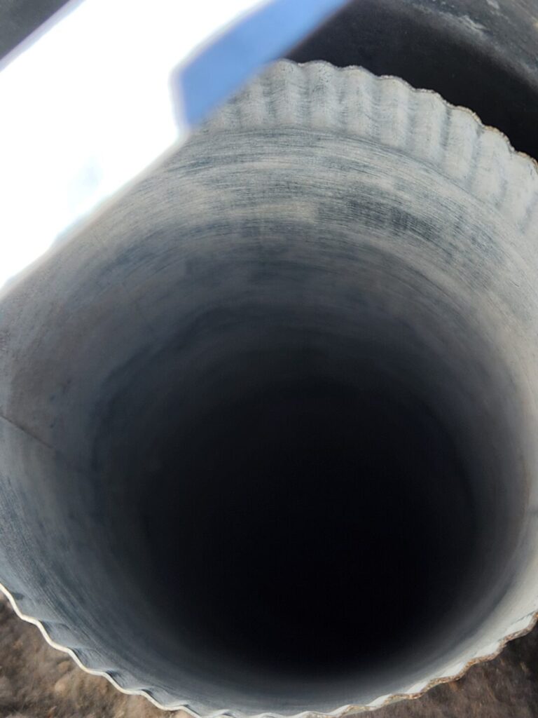 Close-up looking into a cleaned metal dryer exhaust duct at the roof opening.