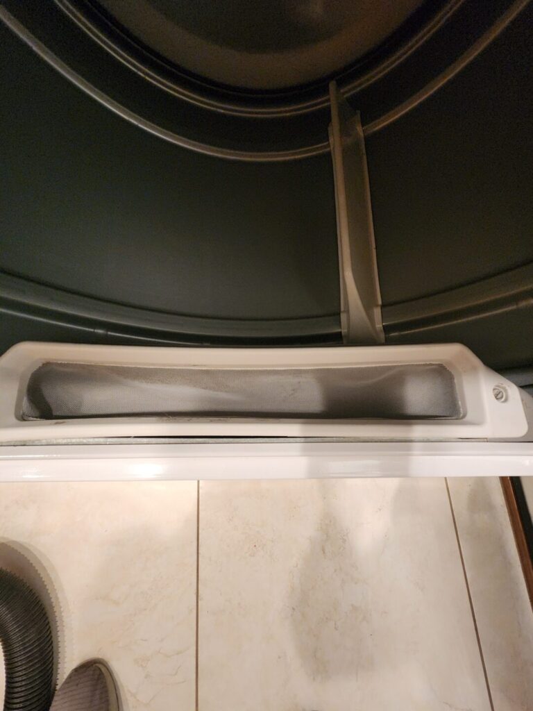 Close-up of the lint catcher area inside an older dryer.